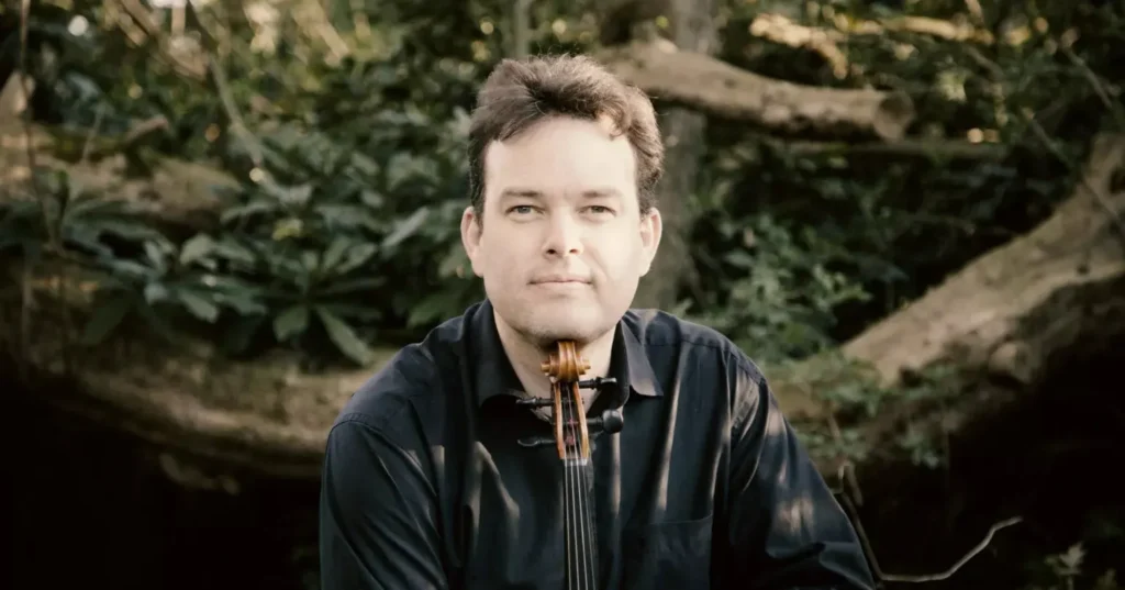 Gareth Lubbe with his chin on the violin with a tree behind